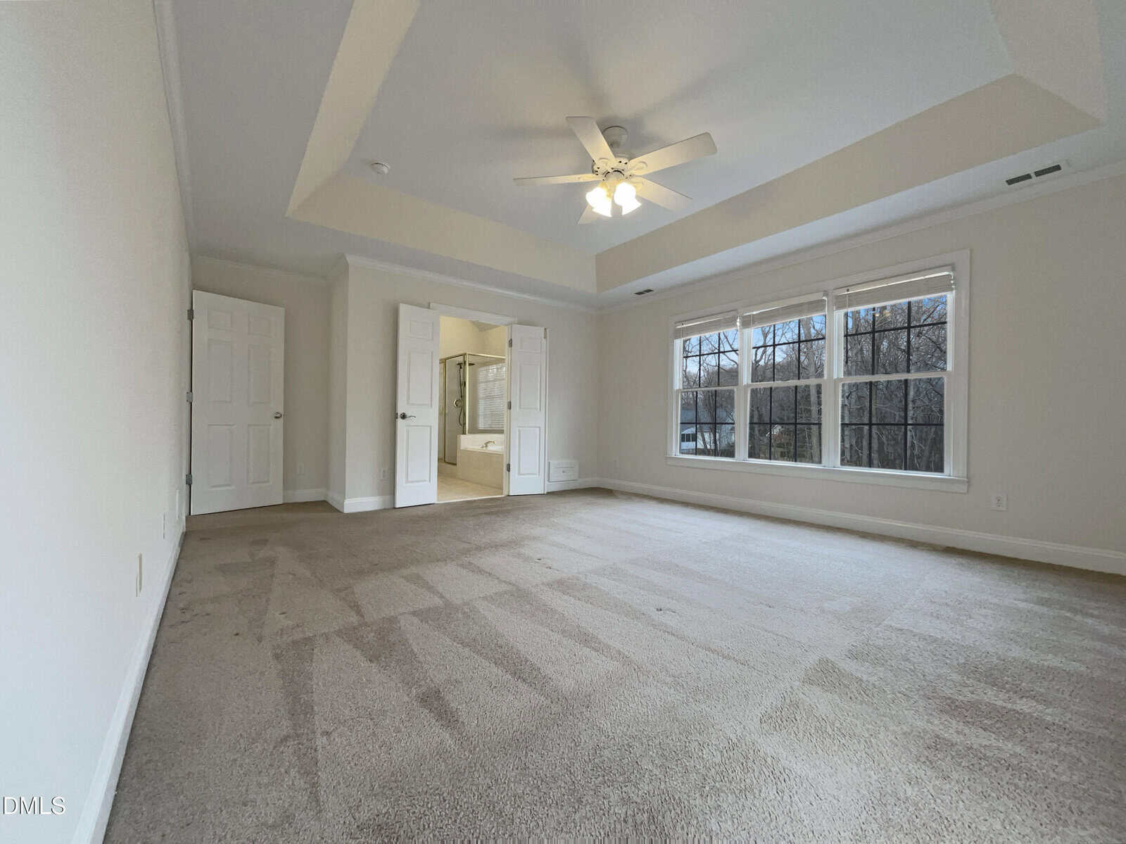 A room with a ceiling fan and windows.
