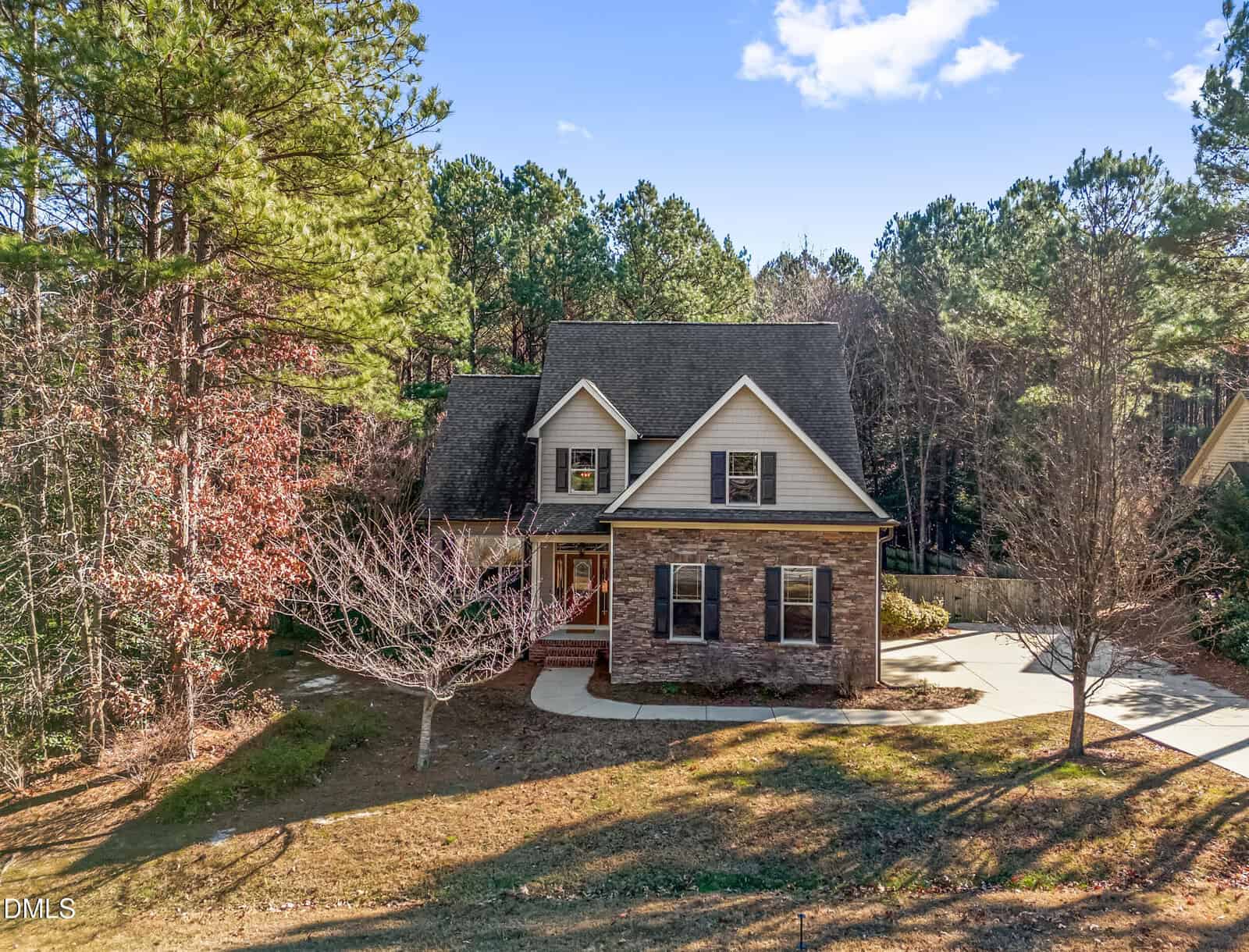 Located at 40 Muirfield Drive in Youngsville, this two-story house features brick and beige siding, a covered front porch, and an attached garage. Surrounded by trees, it sits on a spacious lot with a curved driveway under sunny skies.