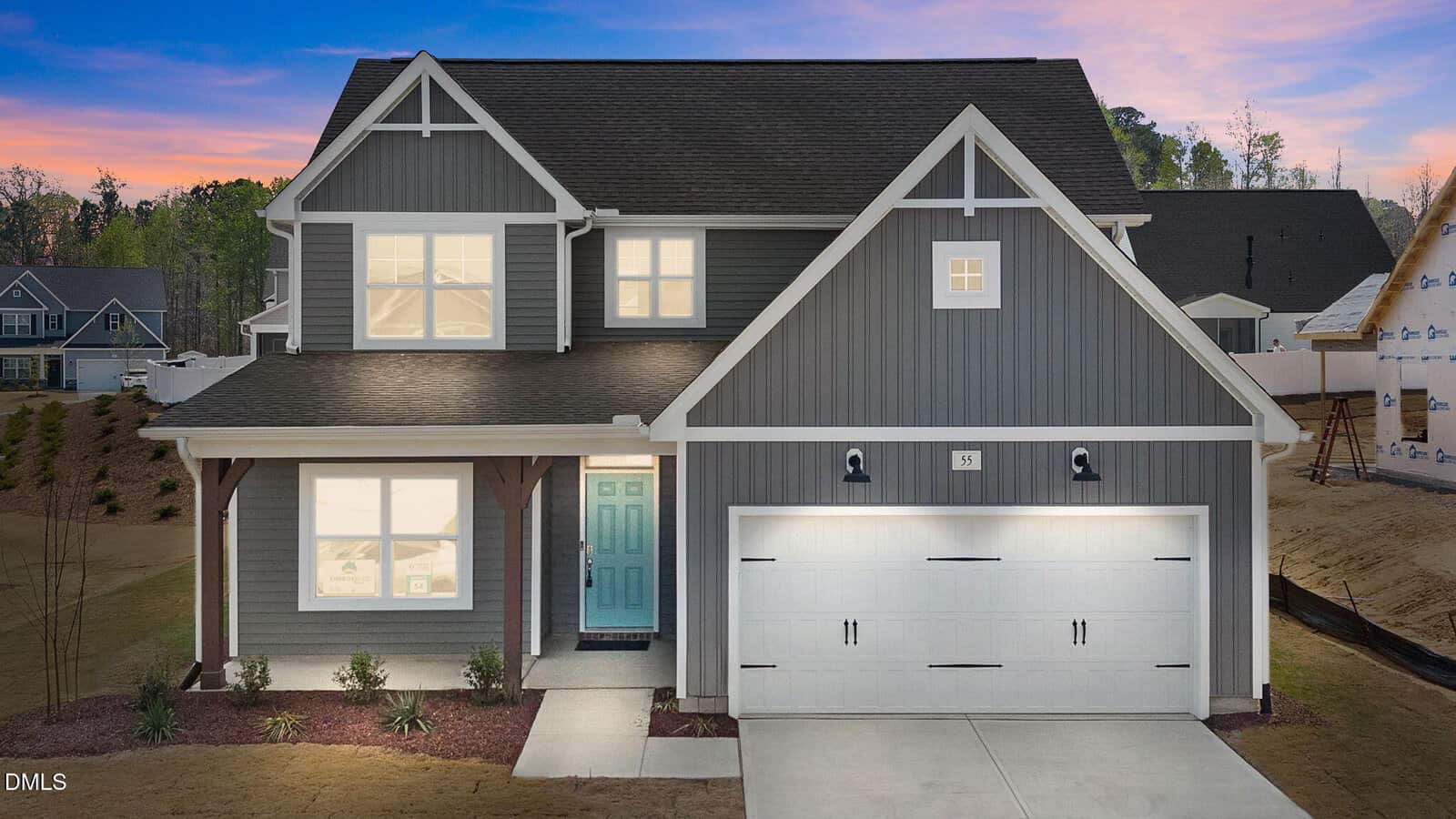 A two-story gray house with white trim, a teal front door, and a double garage lit by exterior lights. The lawn is neatly landscaped with small shrubs, and neighboring houses are visible in the background at dusk.