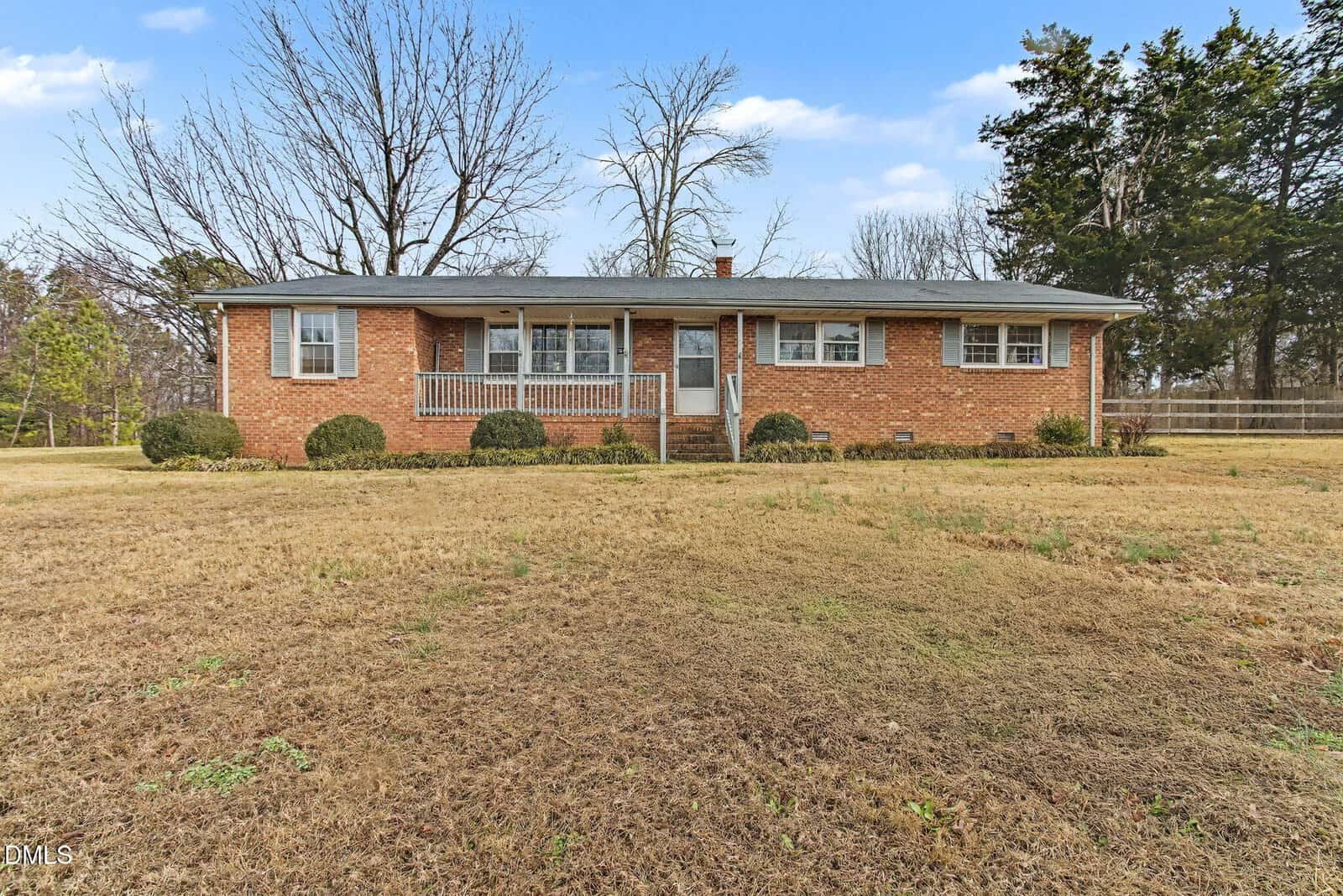 A single-story brick house with a gray roof, white trim, and a small front porch sits on a large grassy lot at 7640 US 15, Oxford, with a few bushes by the foundation and leafless trees in the background.