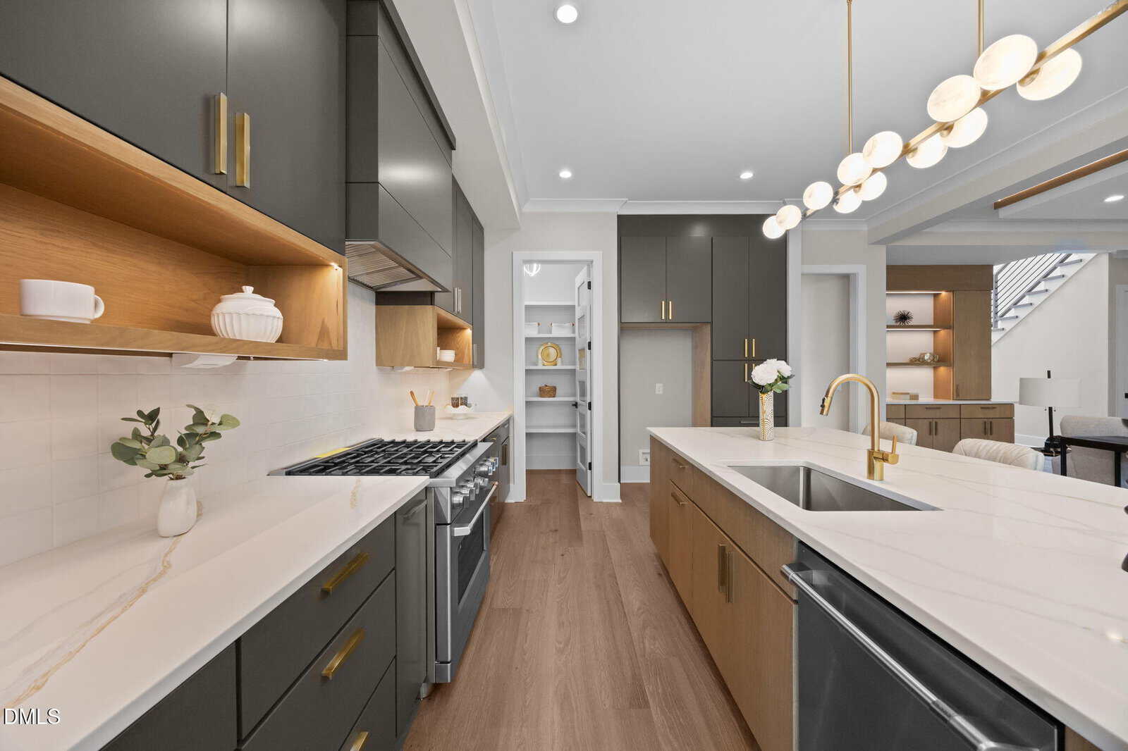 Modern kitchen with black and wood cabinets, gold hardware, white marble countertops, a gas stove, open shelves, pendant lights, and a walk-in pantry. The space is bright with natural light and has a contemporary design.