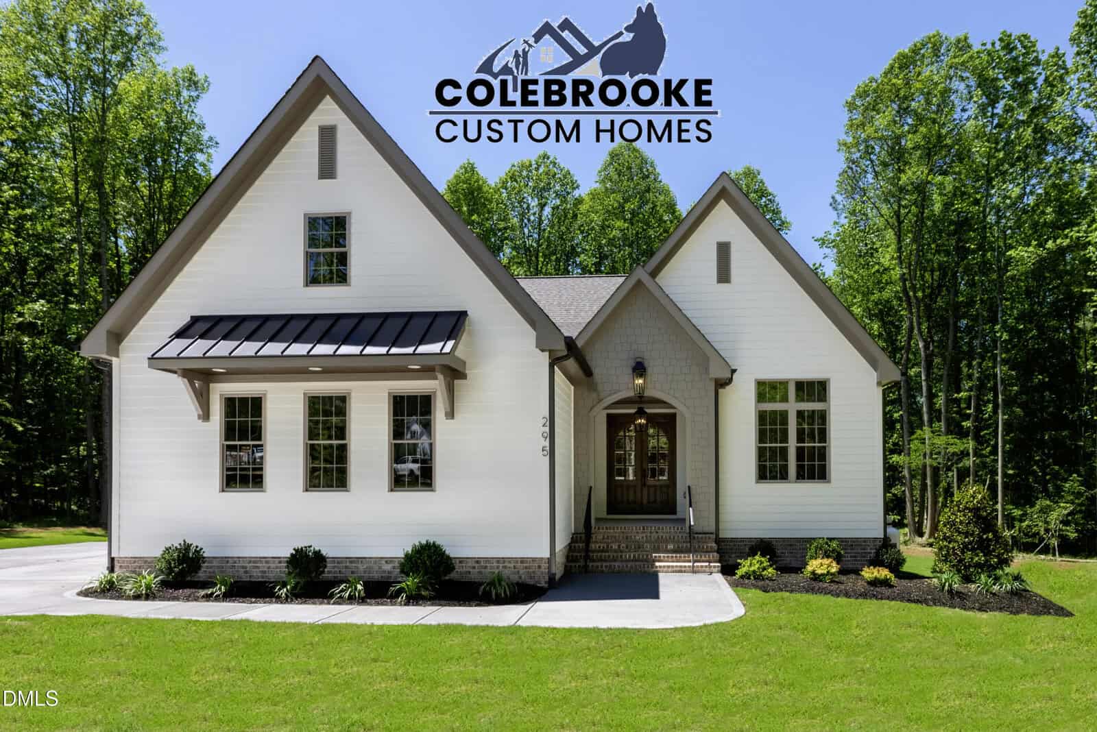 A white modern farmhouse with a gable roof, black trim, and front porch sits on a green lawn in Louisburg at 295 Whistlers Cove. Trees frame the background, with the "Colebrooke Custom Homes" logo displayed above the house.