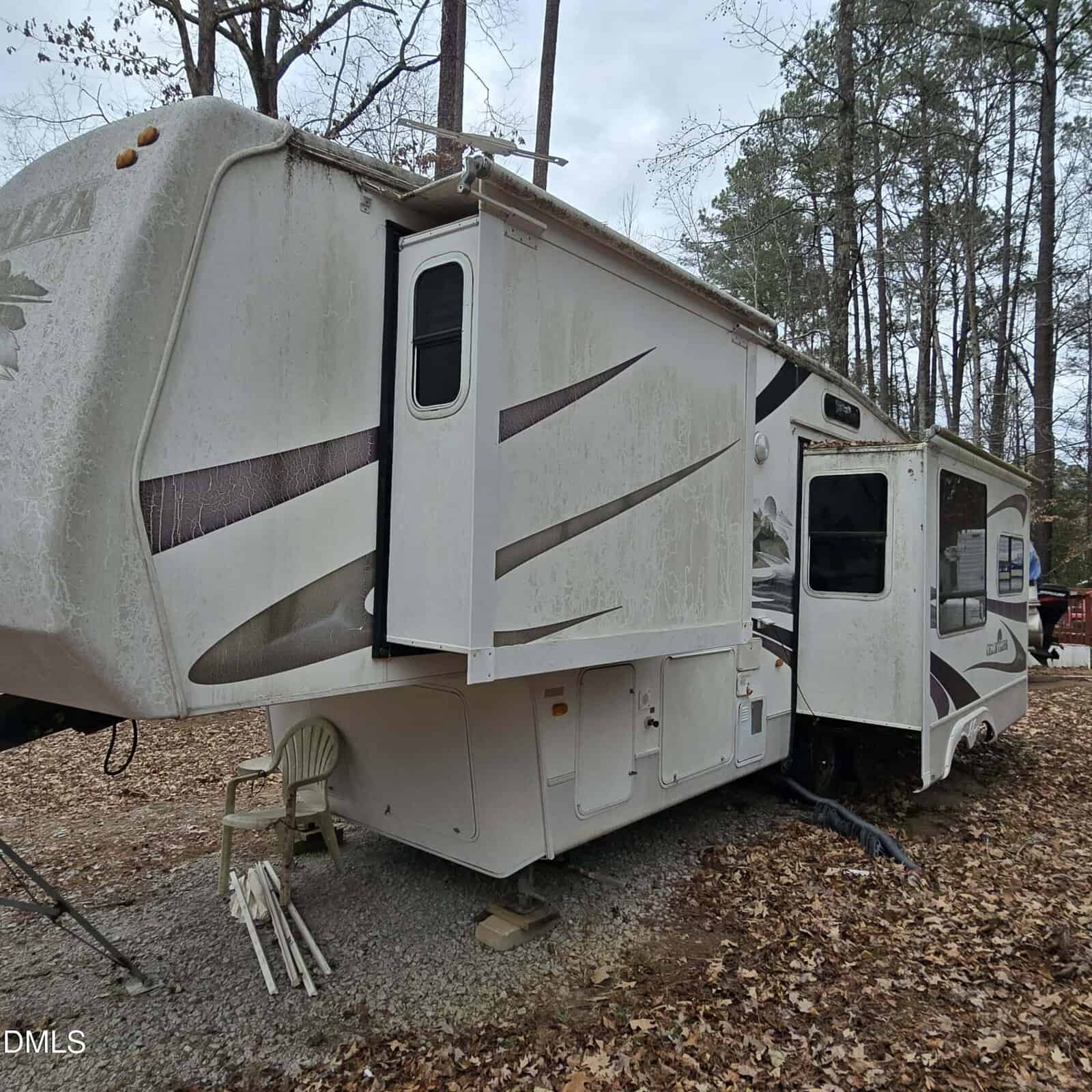 A white rv parked in the woods.
