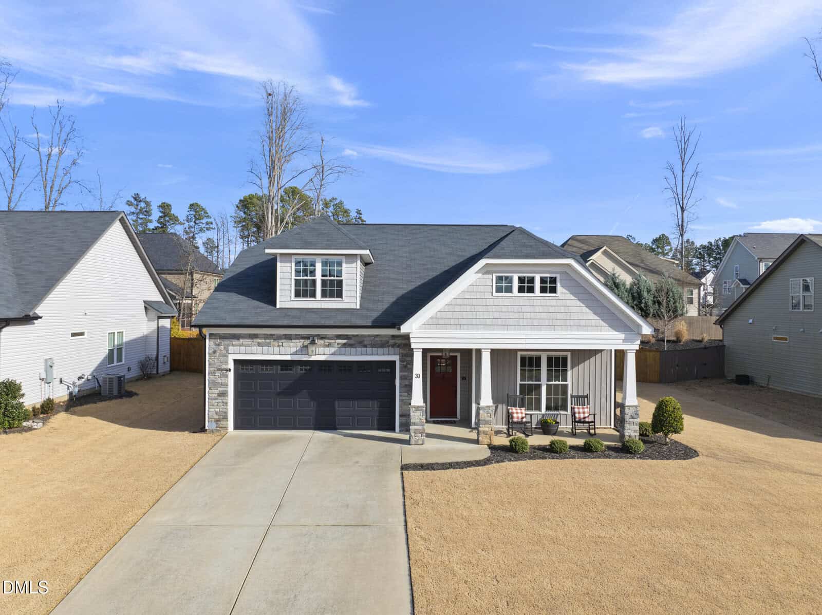 A modern two-story house at 30 Kathleen Court in Youngsville, featuring gray siding, stone accents, a dark garage door, and a front porch with chairs. The home sits on a neatly maintained lawn with minimal landscaping and is surrounded by similar homes.