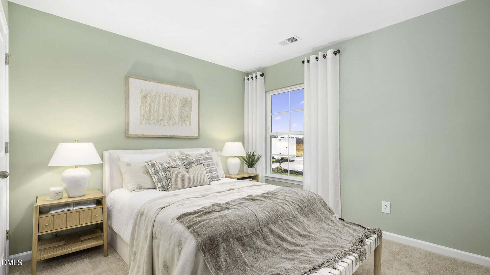 Bright bedroom with light green walls, a large bed with neutral bedding, two wooden nightstands with lamps, a framed artwork above the bed, and a window with white curtains letting in natural light.