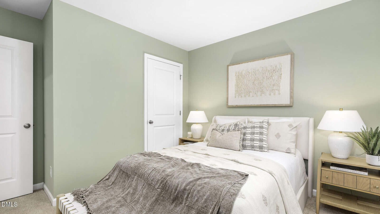 A cozy bedroom with sage green walls, a neatly made bed with neutral bedding and throw pillows, two wooden nightstands with lamps, a potted plant, and a framed artwork above the bed.
