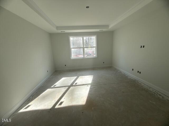 An empty, unfinished room with white walls, a large window letting in sunlight, and a bare concrete floor. The room appears to be under construction or renovation.