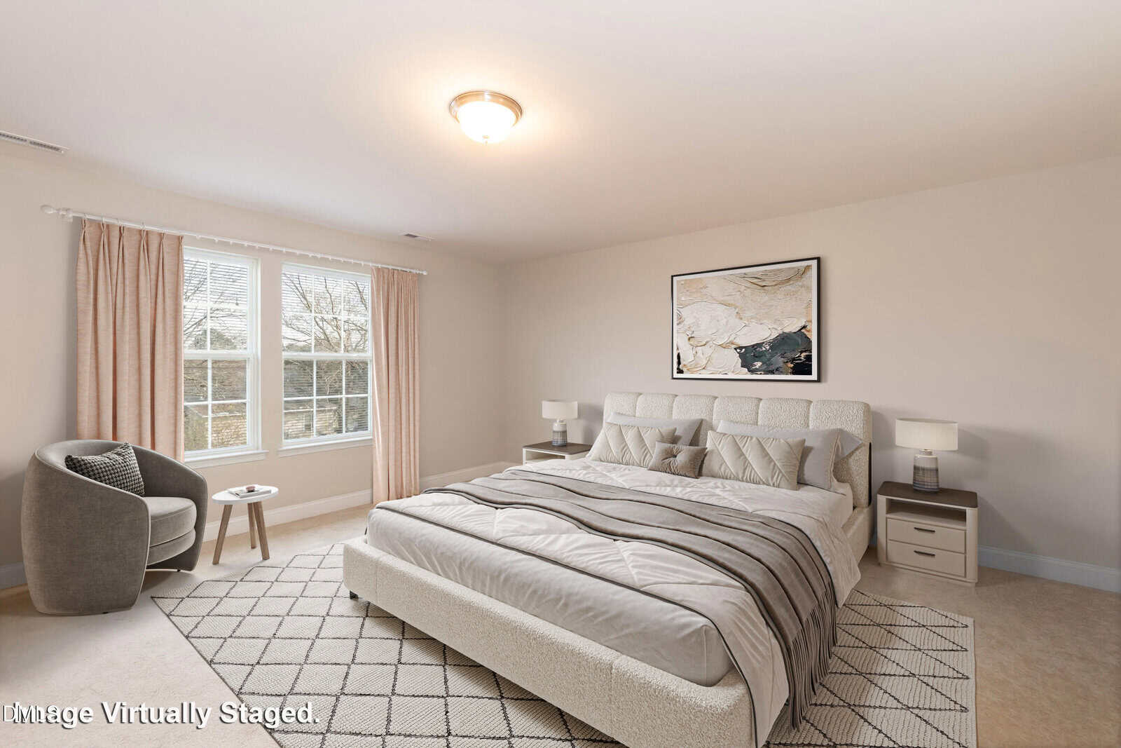 A virtually staged bedroom features a large bed with neutral bedding, two nightstands, a gray armchair, a side table by the window, artwork above the bed, and beige carpet flooring.