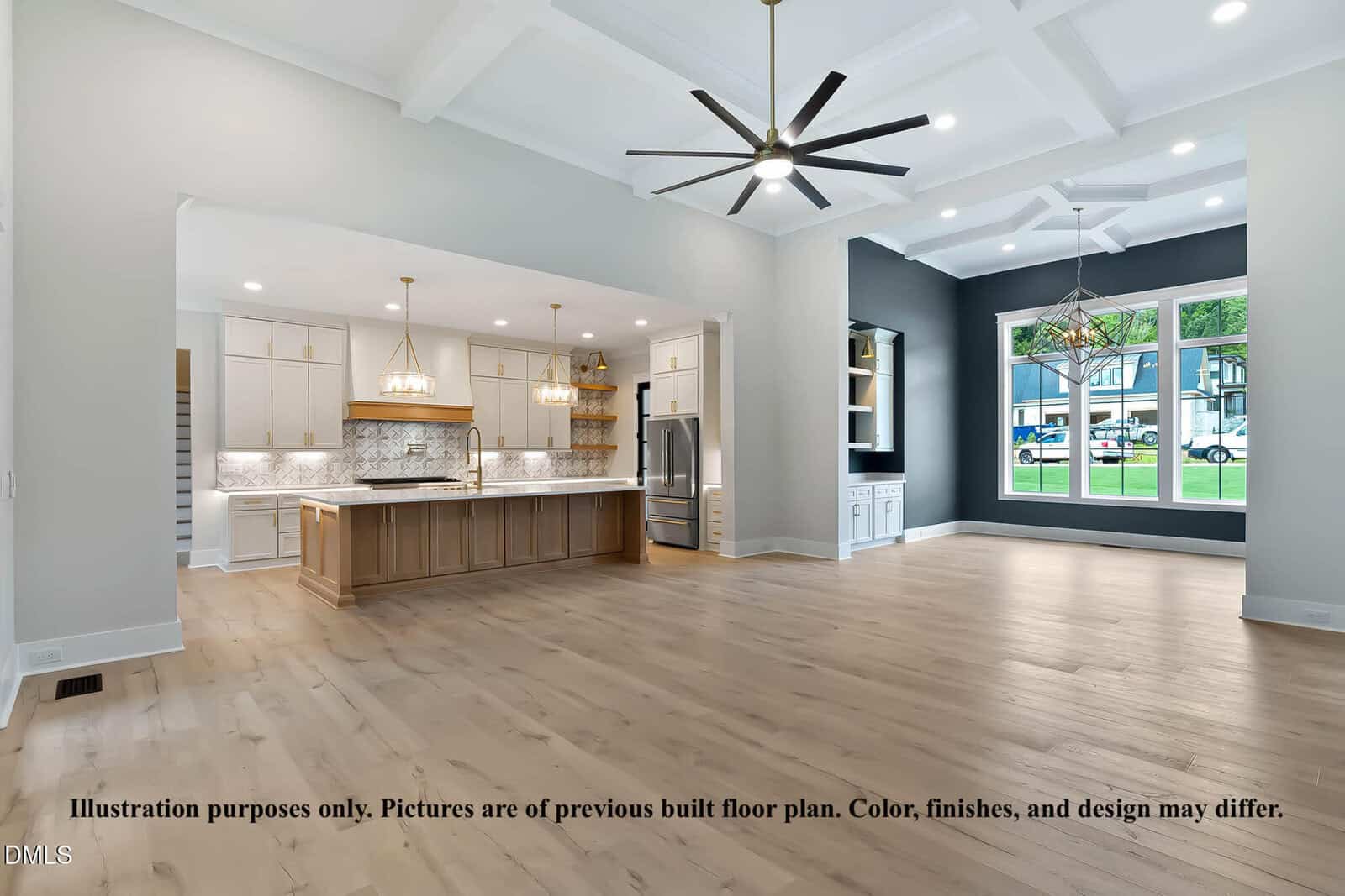 Open-concept living space with light wood floors, a kitchen with white cabinets and a large island, two modern chandeliers, a dark accent wall with built-in shelves, and large windows letting in natural light.