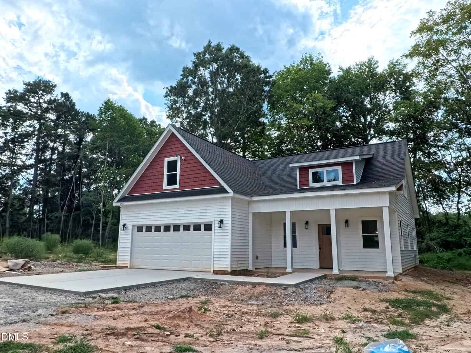A newly built two-story house at 3265 Sims Bridge Road, Kittrell, features a red and white exterior, an attached double garage, a covered front porch, and is surrounded by trees and unfinished landscaping under a partly cloudy sky.