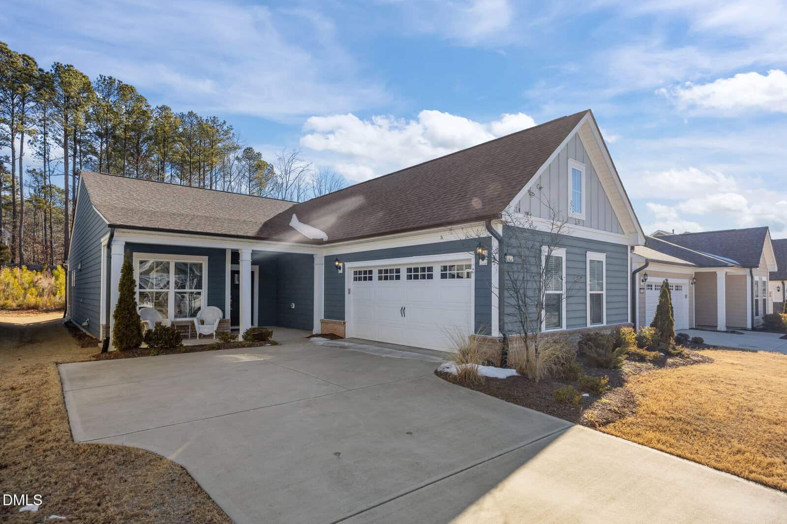 A single-story house at 941 Coast Grade Street in Wake Forest features blue siding, white trim, a two-car garage, and a covered front porch with chairs. The driveway and lawn are neatly maintained, and neighboring homes are visible in the background.