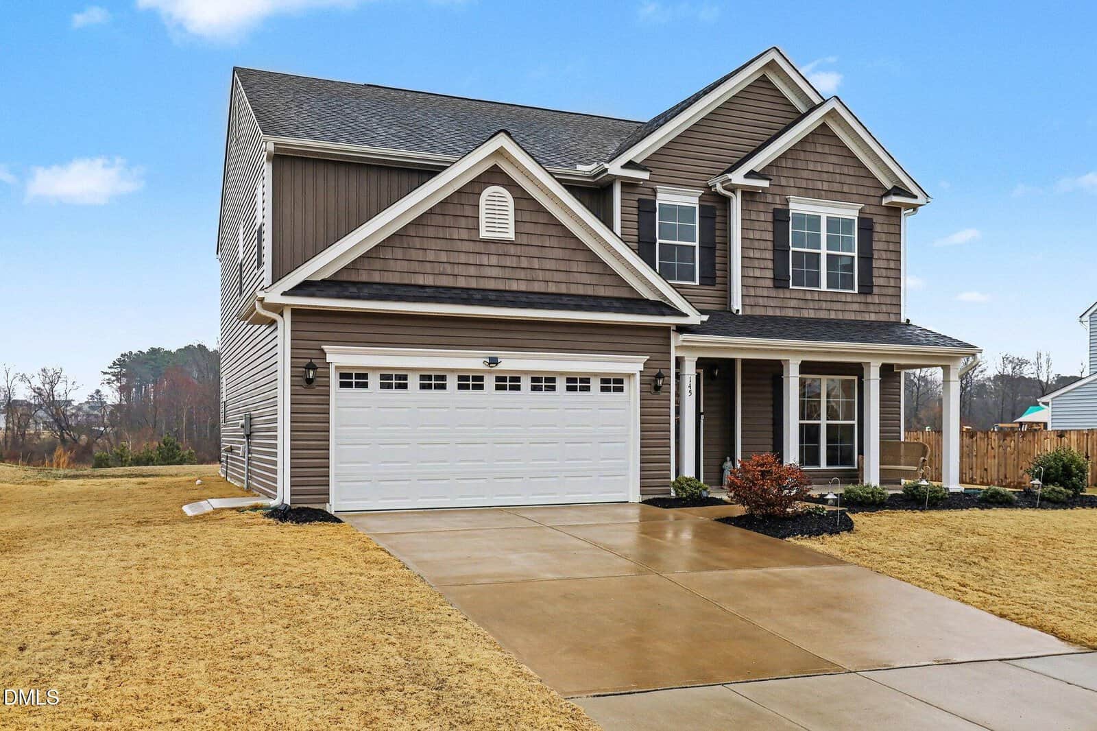 Two-story suburban house with brown siding, white trim, and a double garage located at 145 Mcfarlin Circle in Youngsville. The driveway and yard are visible, featuring minimal landscaping beneath a partly cloudy sky overhead.