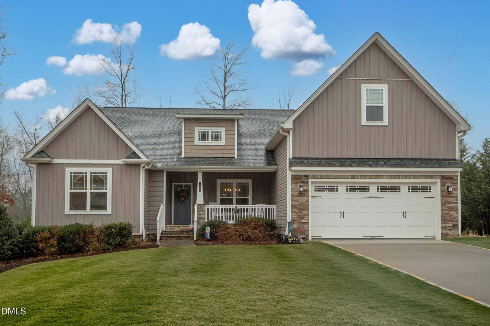 A modern suburban house at 135 Lockamy Lane in Youngsville, featuring gray siding, a front porch, large windows, a double garage, and a well-kept lawn under a blue sky with scattered clouds.