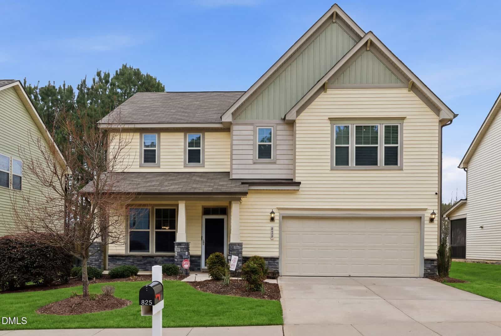 Two-story suburban house with beige siding, green accent gable, and attached two-car garage. Located at 825 Fulworth Avenue in Wake Forest, this home features a front porch, manicured lawn, small shrubs, and a black mailbox with the number 825 by the driveway.