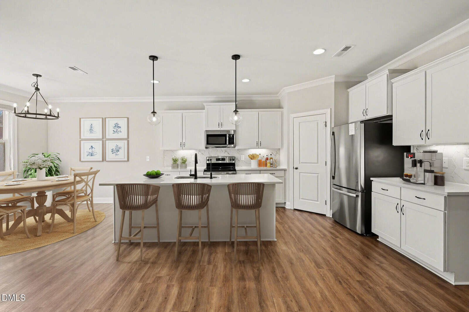 Modern kitchen with white cabinets, stainless steel appliances, a large island with three barstools, pendant lights, and wood flooring. Adjacent dining area with a round table and chairs under a chandelier.
