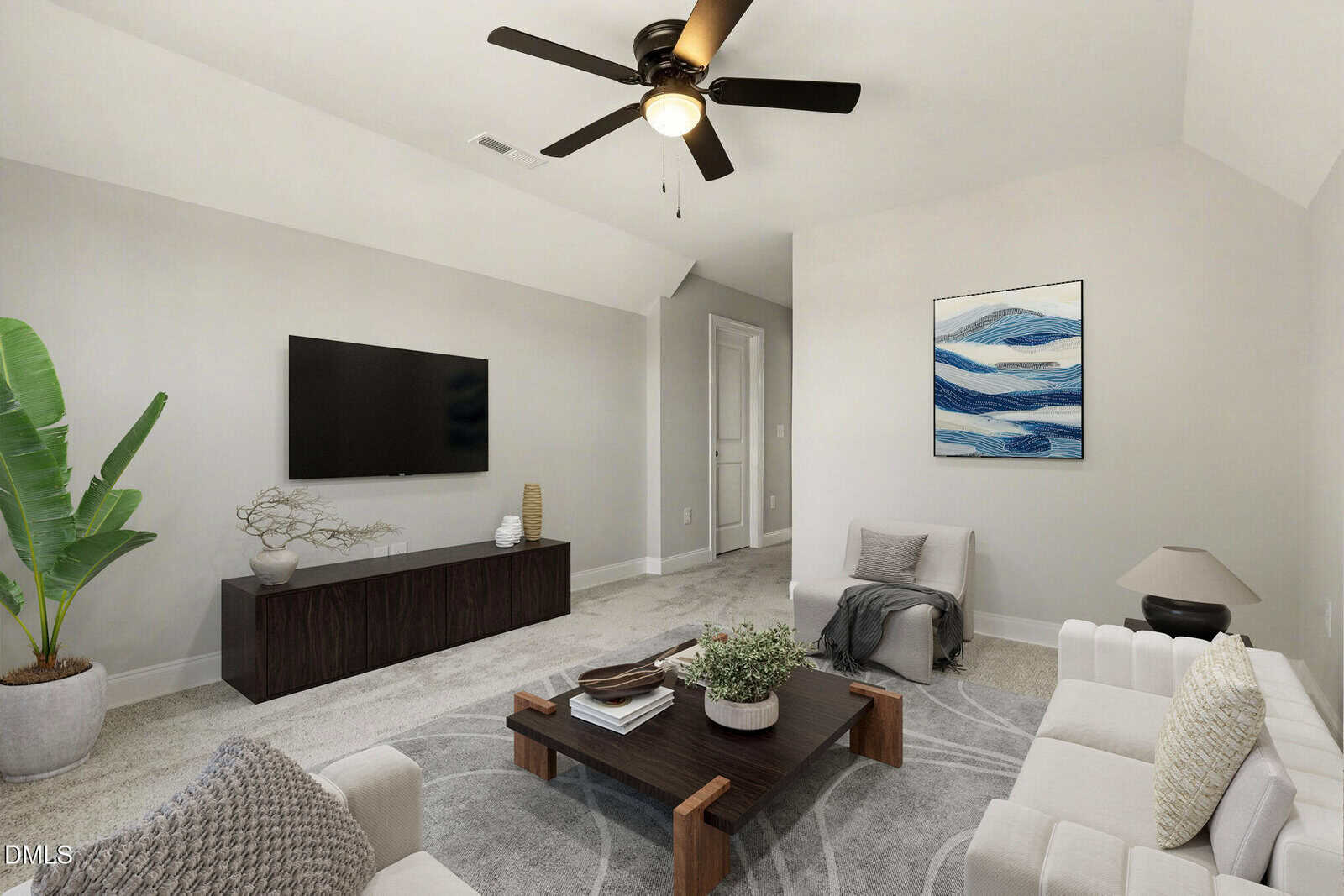 Modern living room with white sofas, a low wooden coffee table, a flat-screen TV on a dark console, abstract wall art, a potted plant, and a ceiling fan. The decor is minimalist with neutral colors and simple accents.