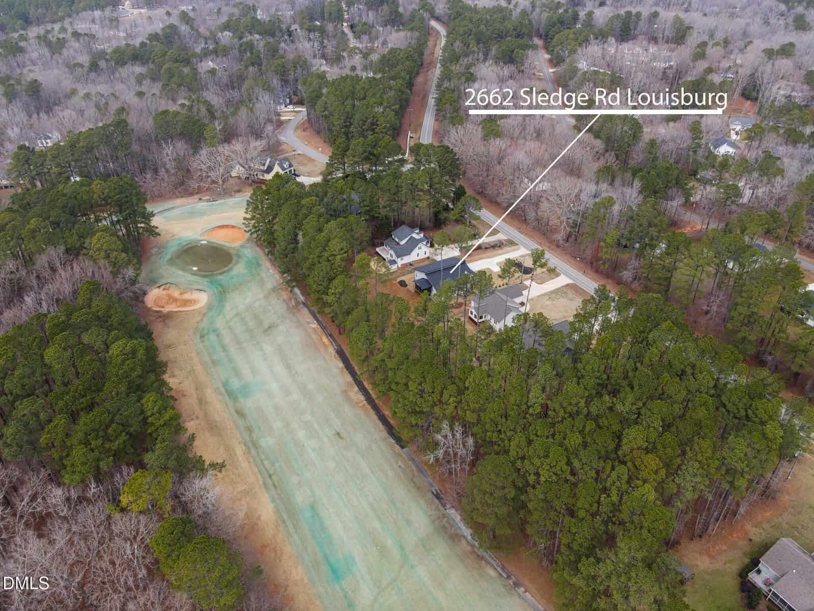 Aerial view of a residential area with houses surrounded by trees and a golf course. A white line and label point to a house at 2662 Sledge Rd, Louisburg.