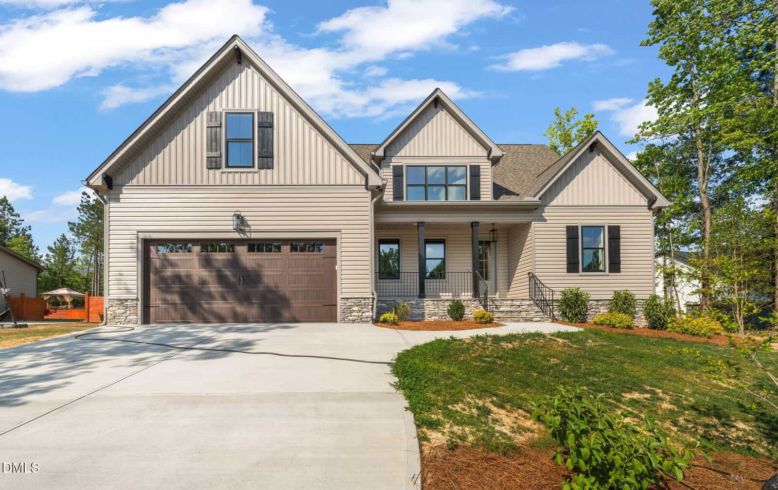 A modern suburban house at 350 Pilot Ridge Road in Zebulon, with beige siding, stone accents, and a large brown garage door, set on a wide driveway and surrounded by landscaped lawn and trees under a blue sky.
