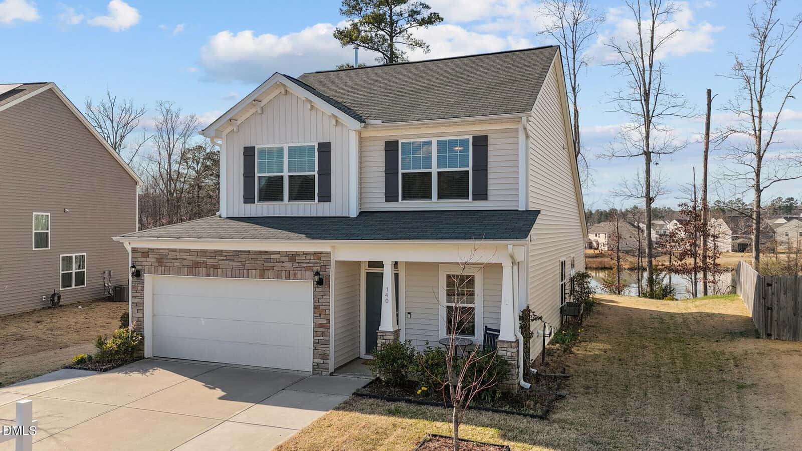 Two-story suburban house with light siding and stone accents at 140 Hawksbill Drive, Franklinton. Features a two-car garage, small front porch, and neatly maintained lawn in a residential neighborhood under a partly cloudy sky.