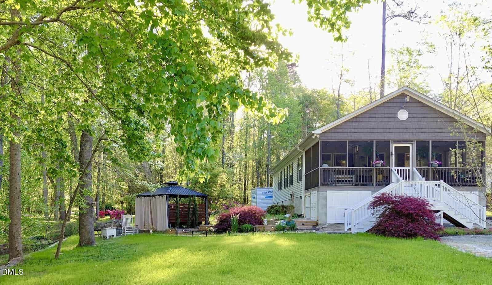 Nestled on 101 Bow Drive in Louisburg, this cozy house features a large screened porch, lush green trees, and a well-kept lawn. A charming gazebo and vibrant flowering bushes complete the sunlit yard.
