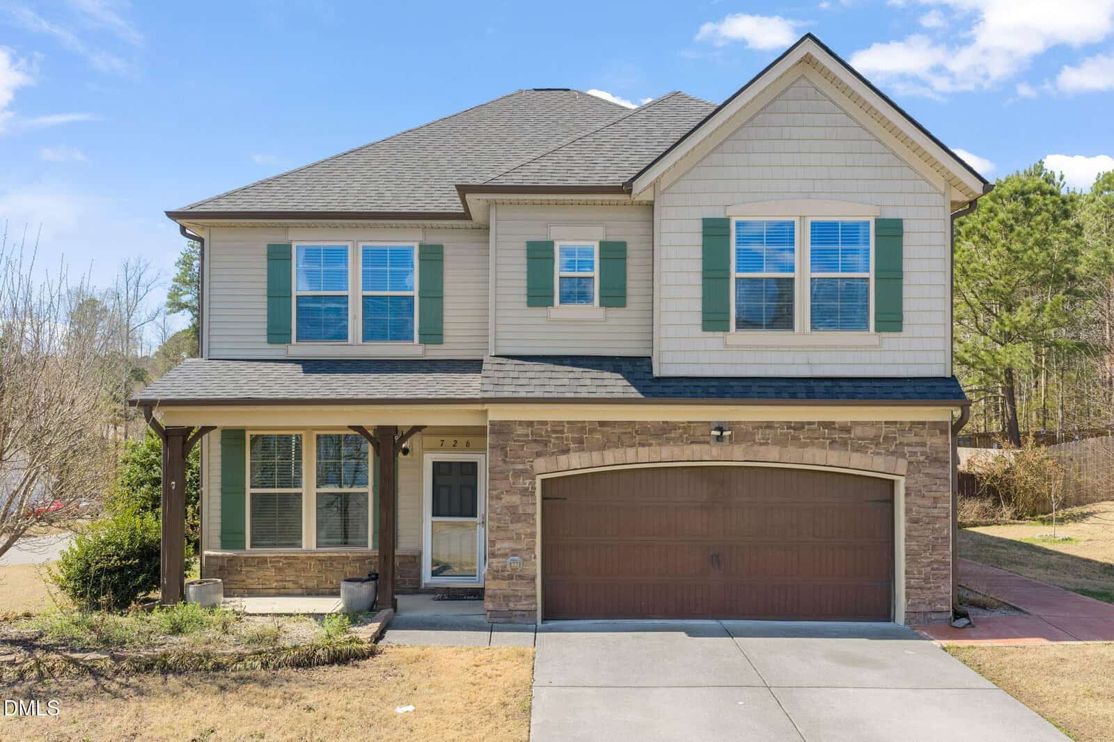 Two-story suburban house at 726 Forrest Lane in Creedmoor, featuring beige siding, stone accents, green shutters, and a double garage. The front yard has sparse grass and small shrubs, while the driveway leads to the garage. Mature trees are visible in the background.