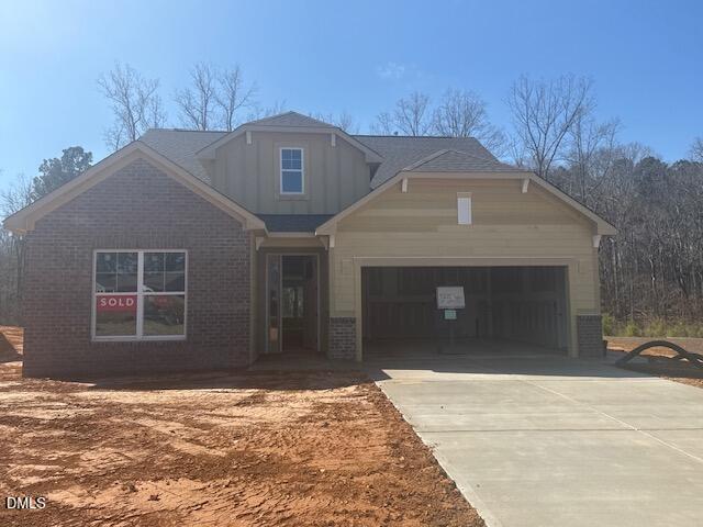 A newly constructed single-family house with a sold sign in the window, located at 200 Sawtooth Oak Lane in Youngsville. The home features a two-car garage, unfinished yard, and a concrete driveway on a sunny day. Leafless trees are visible in the background.