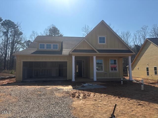 A newly constructed two-story house with tan siding, white trim, a two-car garage, covered porch, and “sold” sign in the front window sits at 210 Sawtooth Oak Lane in Youngsville. The yard is unfinished with exposed dirt and a gravel driveway.