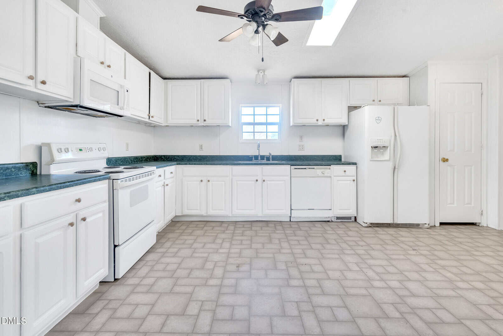 Spacious kitchen with white cabinets, white appliances, green countertops, a ceiling fan, tiled floor, and a window above the sink letting in natural light.