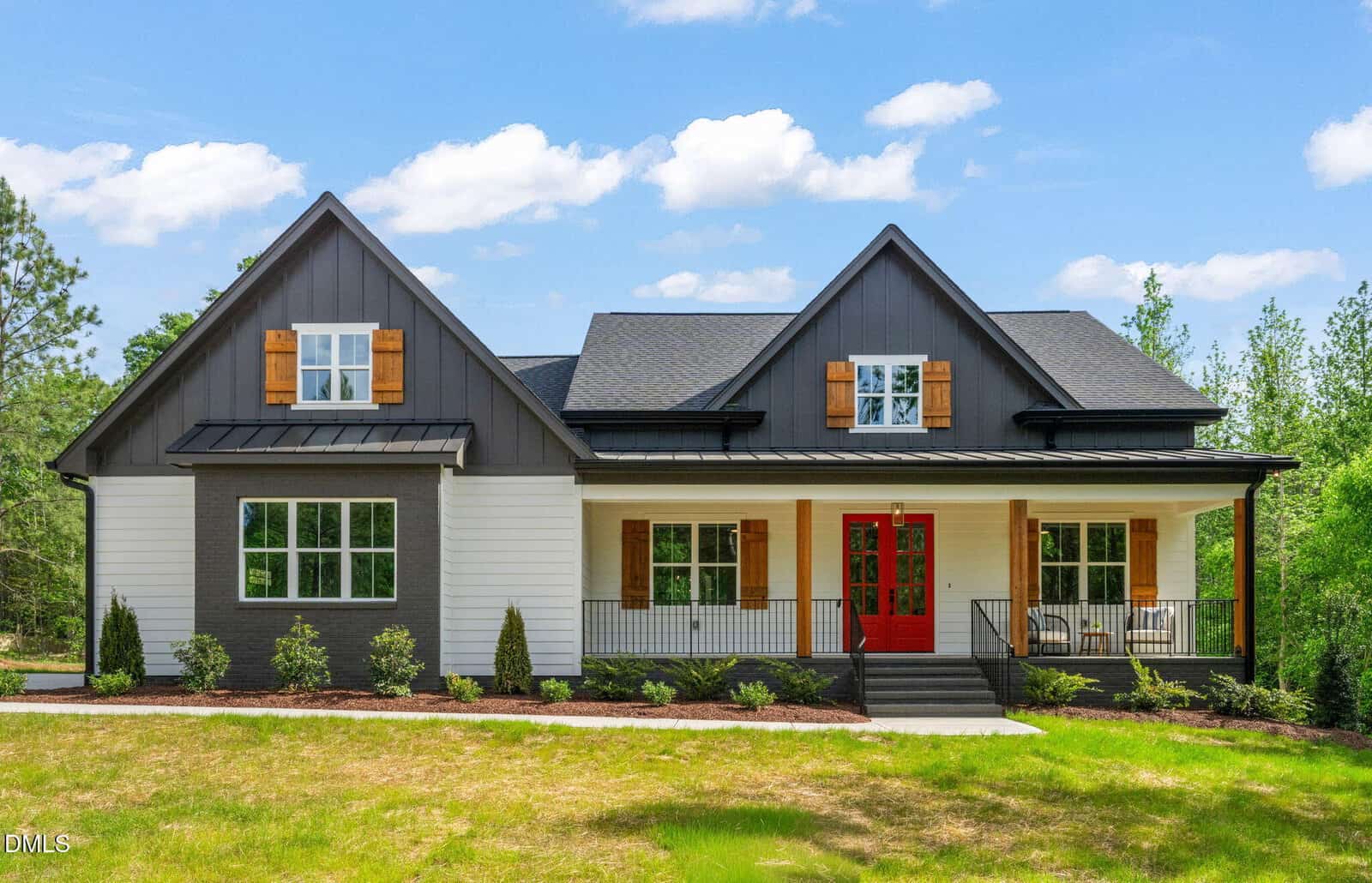 Modern two-story farmhouse at 340 Pilot Ridge Road, Zebulon, with black and white exterior, a bright red front door, wood shutters, covered porch with black railing, and well-kept landscaping under a blue sky with white clouds.
