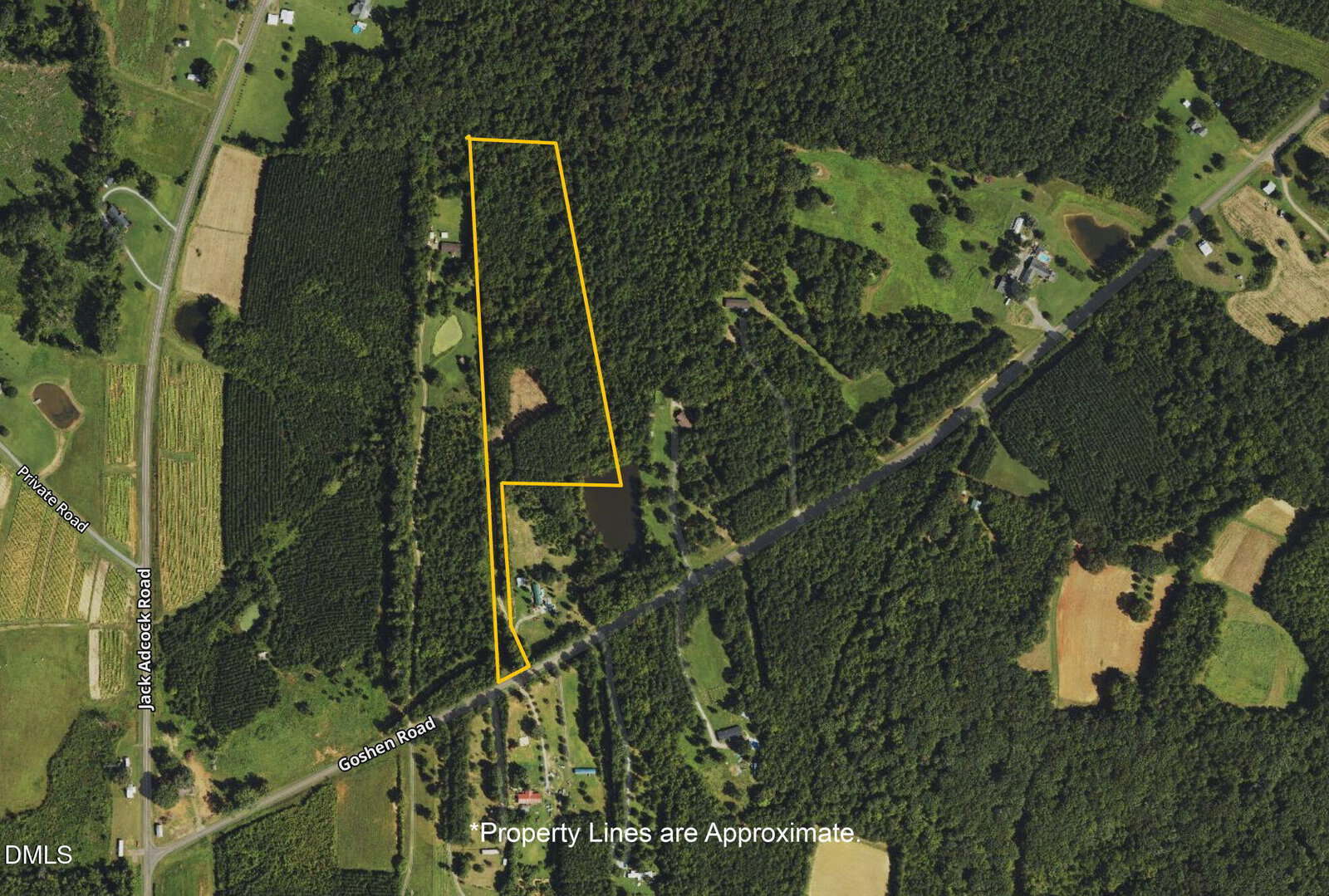 Aerial view of a rural area with fields, houses, and forests. Yellow lines outline a parcel of land, indicating approximate property boundaries. Roads and scattered homes are visible nearby. Text notes the boundaries are approximate.