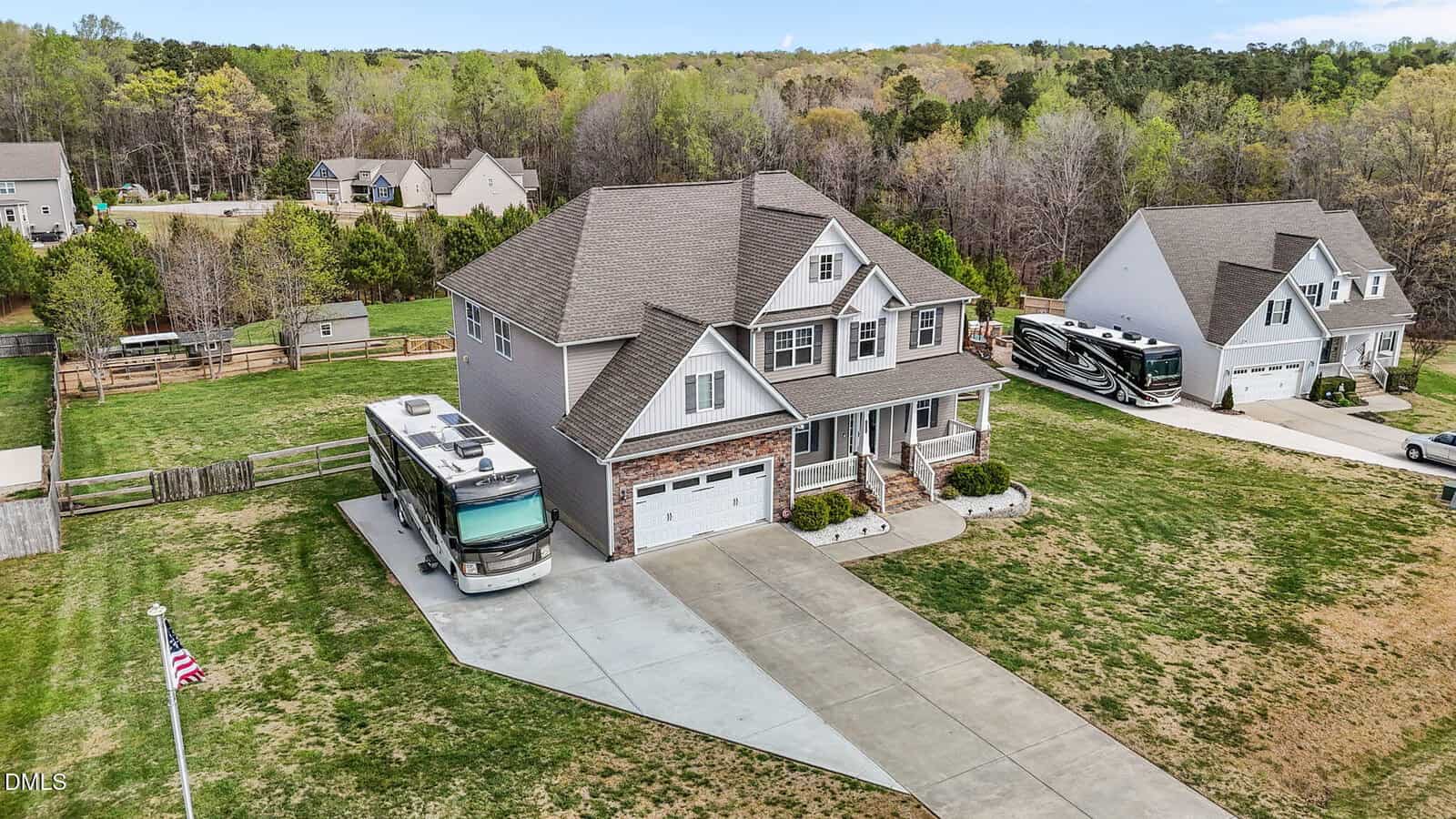 A two-story suburban house with a three-car garage, a motorhome parked in the driveway, and a large yard. There are neighboring houses, trees, and RVs visible in the background.