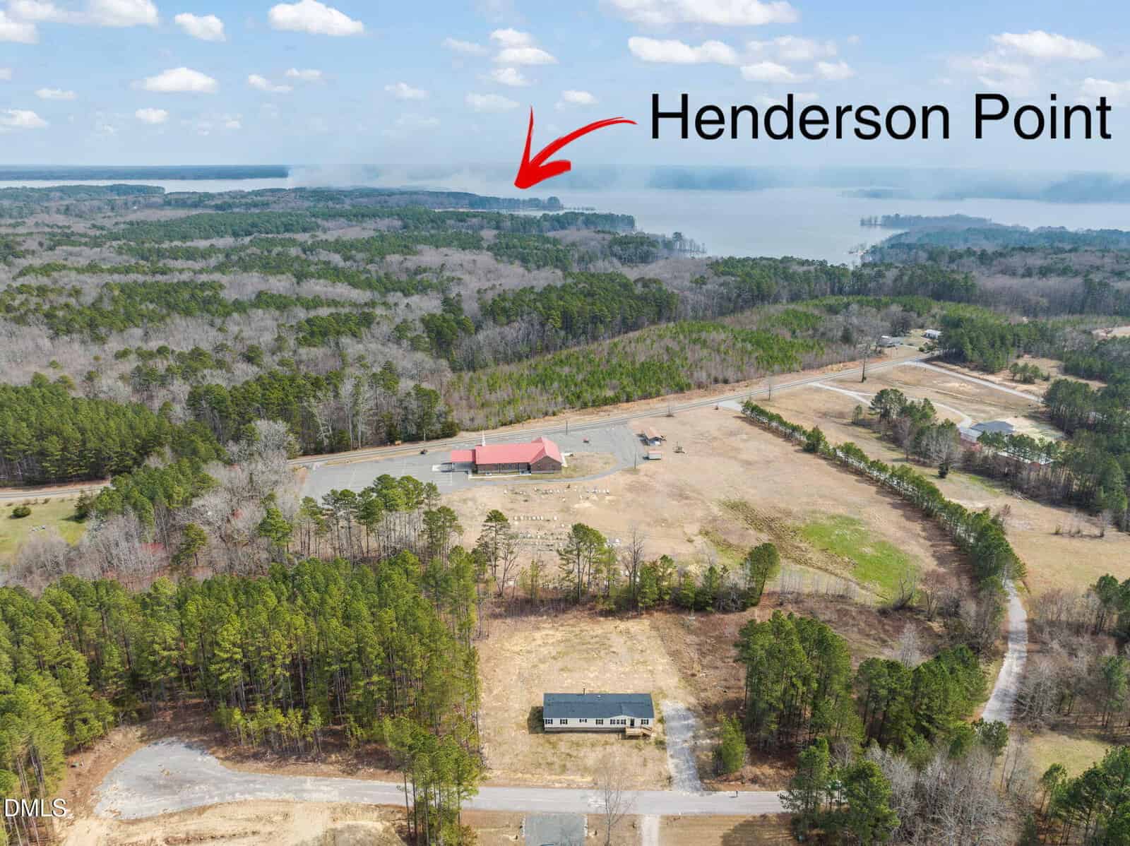 Aerial view of a forested area near a large lake, with a red-roofed building and a road. An arrow points to a distant land area labeled “Henderson Point” by the water.