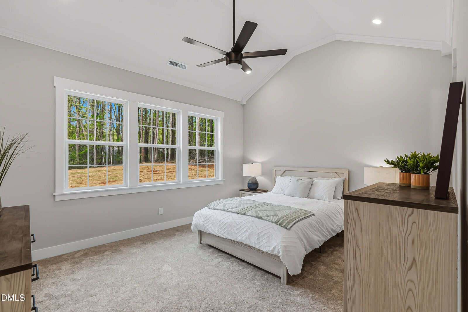 Modern bedroom with large windows, a bed with white bedding, a ceiling fan, two nightstands with lamps, and a wooden dresser. Neutral color scheme with view of trees outside.