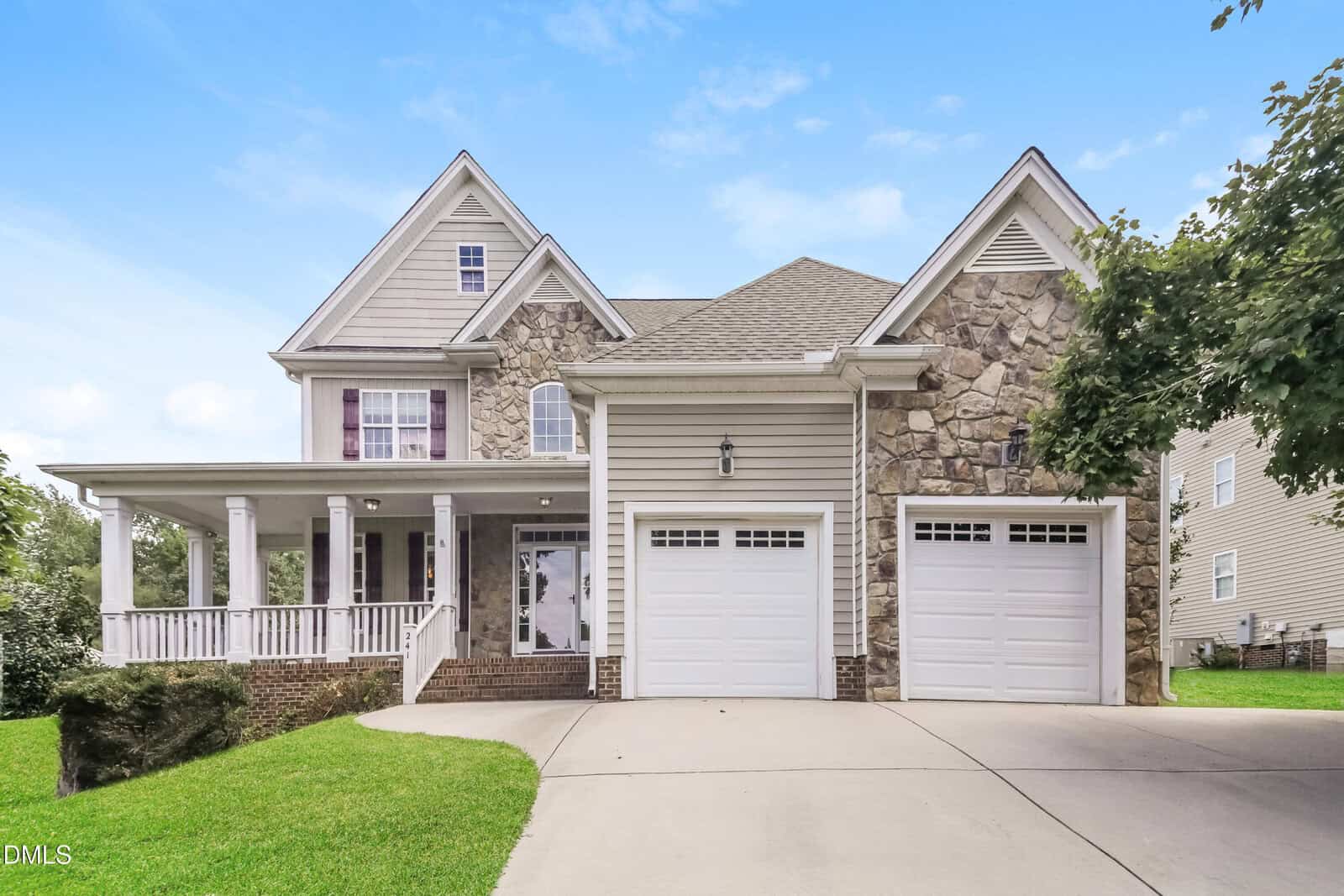 Located at 241 Plantation Drive in Youngsville, this two-story suburban house features a stone and siding exterior, a wraparound front porch, two white garage doors, and a curved driveway set against a blue sky.