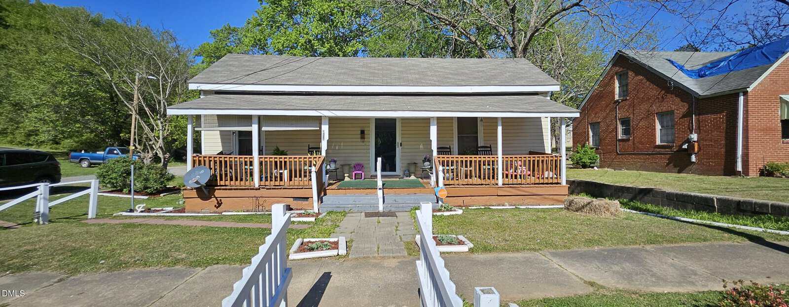 A white, single-story house with a covered front porch, wooden railings, and steps leading to the entrance sits at 313 Granville Street in Oxford. The yard is fenced, and a neighboring brick house is visible to the right. Trees and a blue sky are in the background.
