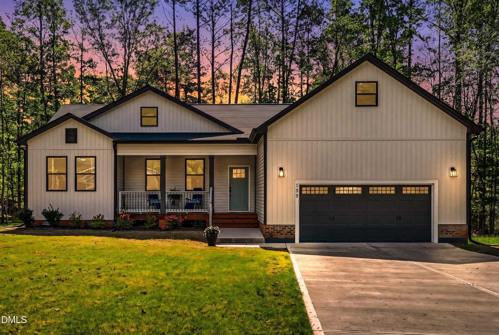 A single-story modern farmhouse at 139 Hatchet Cove, Louisburg, with white siding, black trim, a covered front porch, and a two-car garage, set against a background of tall trees at sunset. A concrete driveway leads to the front entrance.