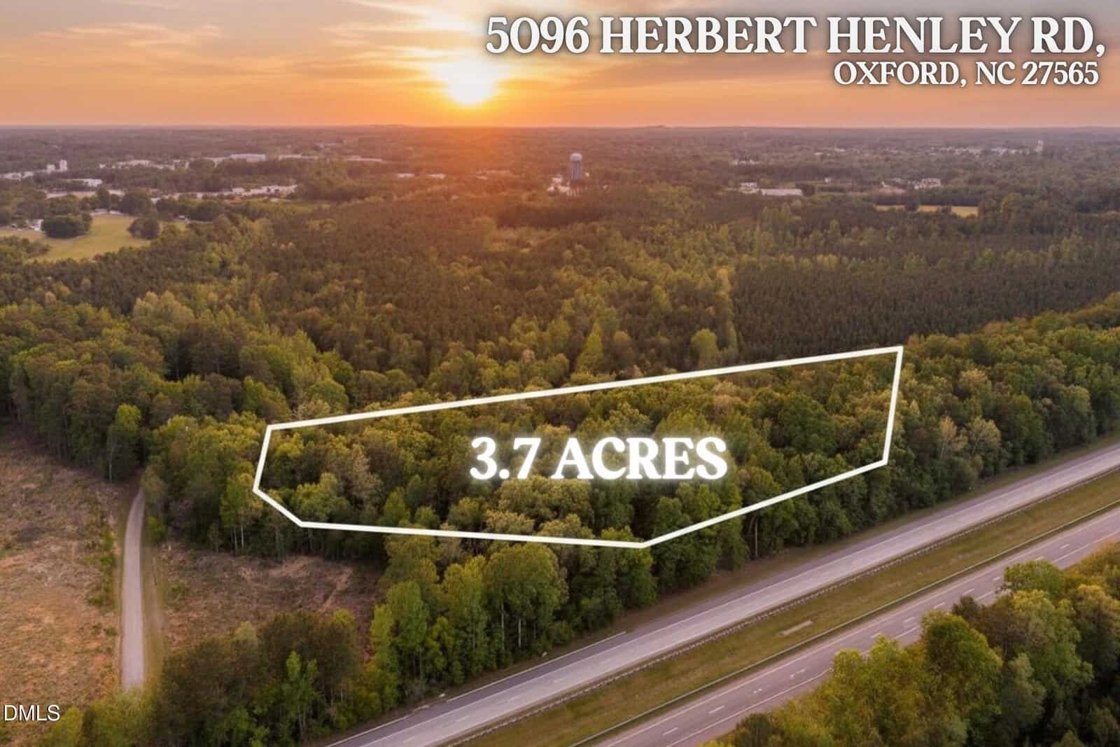 Aerial view of a wooded 3.7-acre lot outlined in white near a road at sunset, with the address “5096 Herbert Henley Road, Oxford, NC 27565” written at the top of the image.