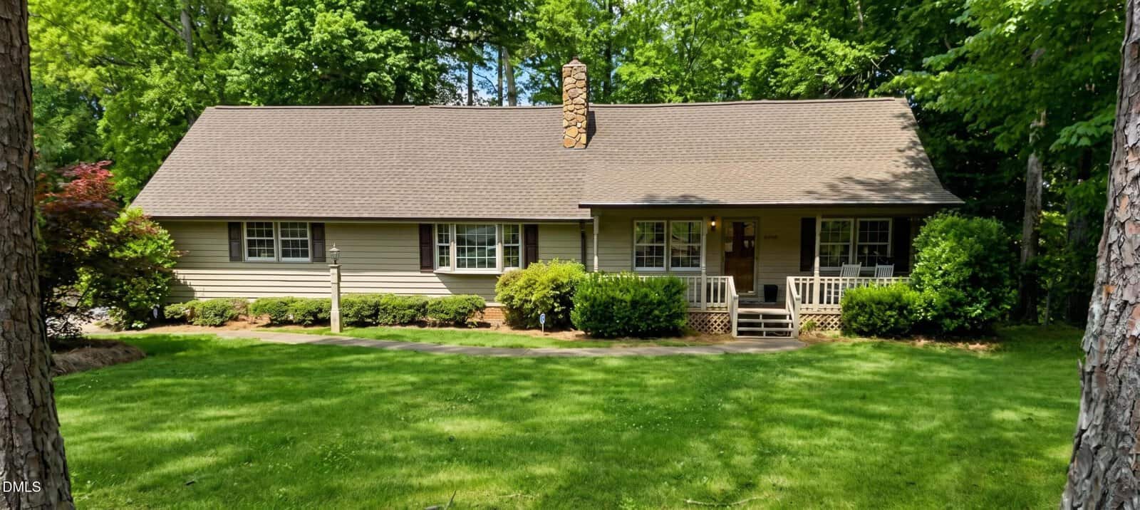 Single-story house at 1602 Peace Street with beige siding, a pitched roof, stone chimney, white-framed windows, and a small porch. The grassy yard features shrubs and trees, nestled in the tranquil Henderson neighborhood.