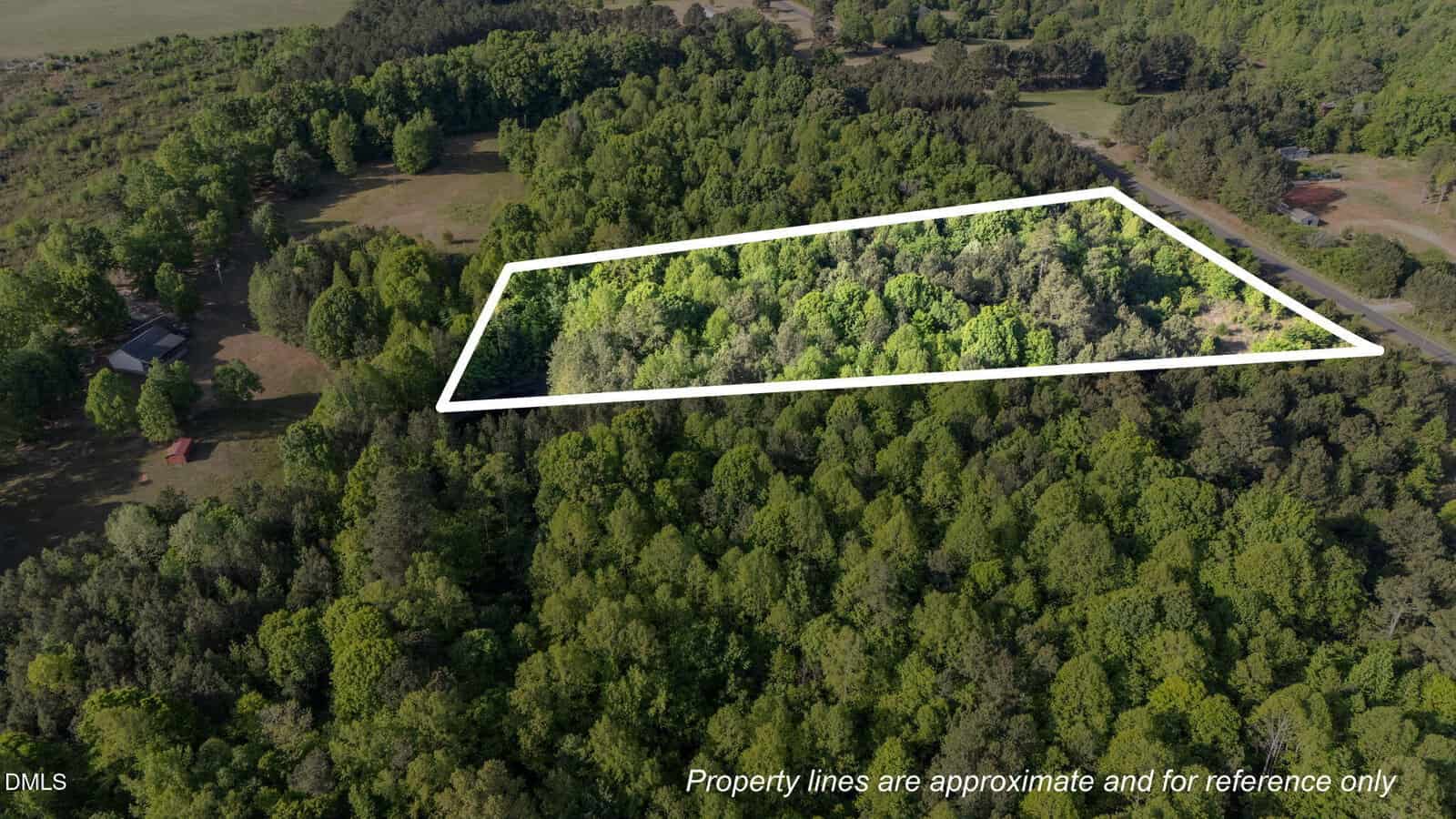 Aerial view of a wooded area with an outlined section indicating approximate property lines. Text at the bottom notes that the boundaries are for reference only. Lush green trees surround the highlighted plot.