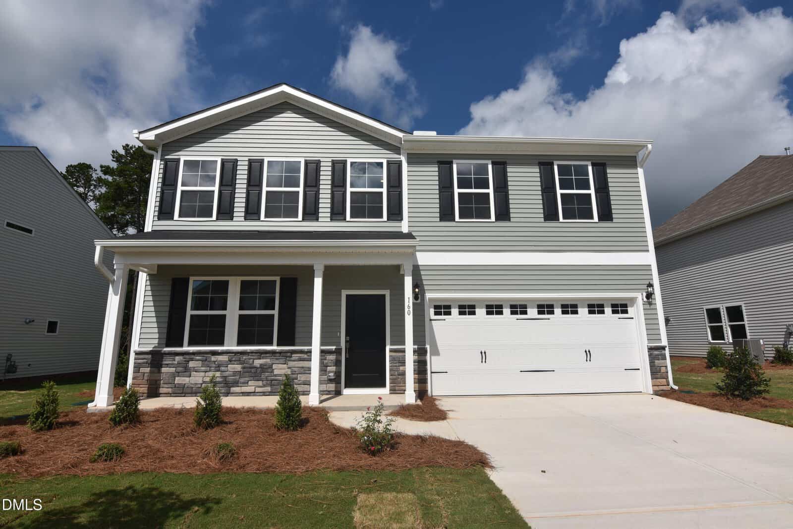 Two-story suburban house with gray siding, white trim, black shutters, a covered front porch, double garage, and landscaped yard with small shrubs and mulch located at 160 Sugarmaple Way in Youngsville. The sky is partly cloudy.