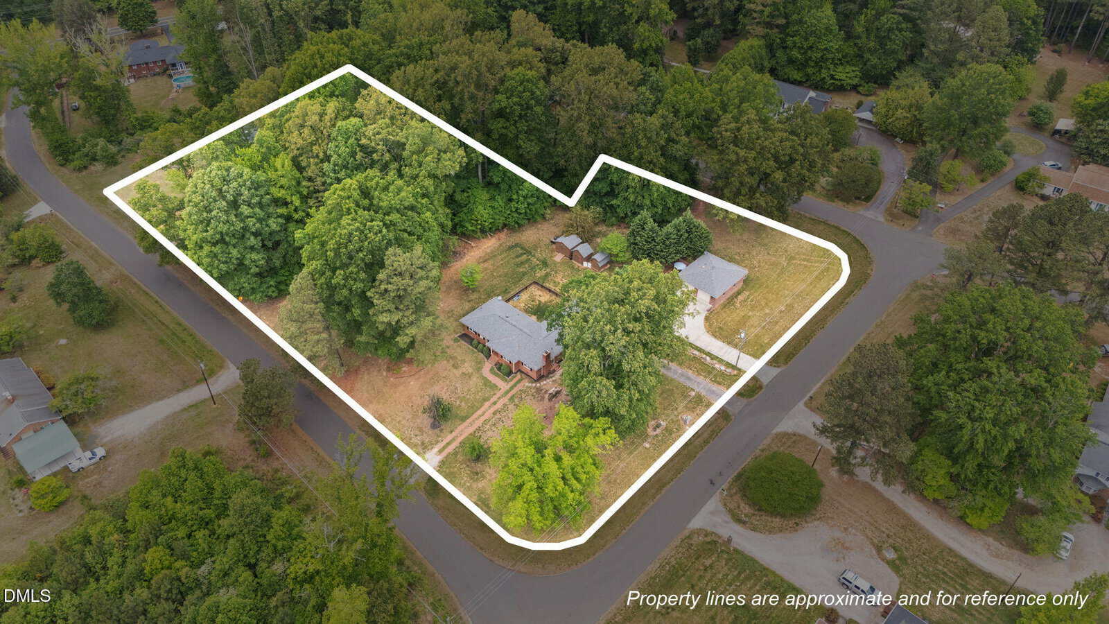 Aerial view of a residential property outlined in white, showing a house, trees, and open lawn, surrounded by streets and other homes. Text notes that property lines are approximate and for reference only.