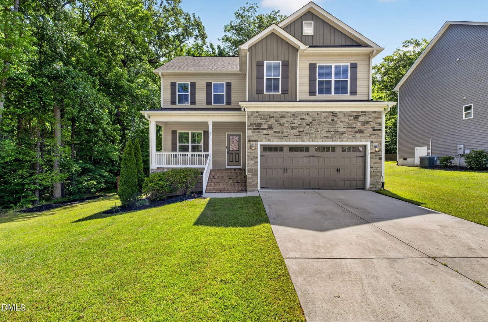 Charming two-story suburban home at 60 Prospectus Lane in Franklinton, featuring a brick and siding exterior, double garage, covered front porch, and a well-maintained lawn surrounded by trees and neighboring houses.