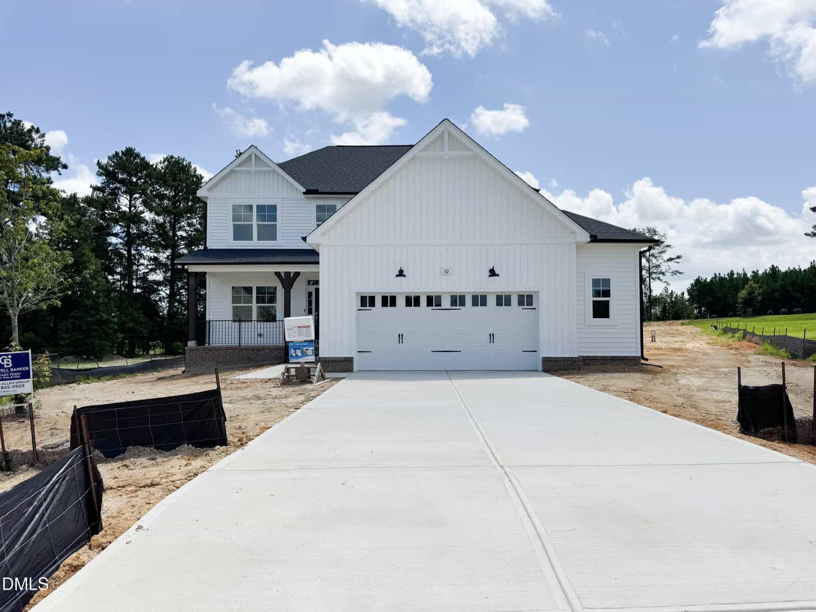 A newly constructed two-story white house at 10 Diamond Creek Drive, Zebulon, featuring a covered porch, double garage, and a wide concrete driveway. There are trees in the background and a for-sale sign on the left side of the property.