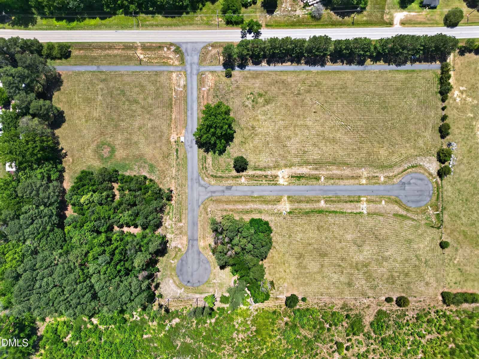Aerial view of a cul-de-sac at 10 Skyline Drive, Louisburg, with a T-shaped road surrounded by grassy fields, patches of trees, and bordered by a main road at the top of the image.