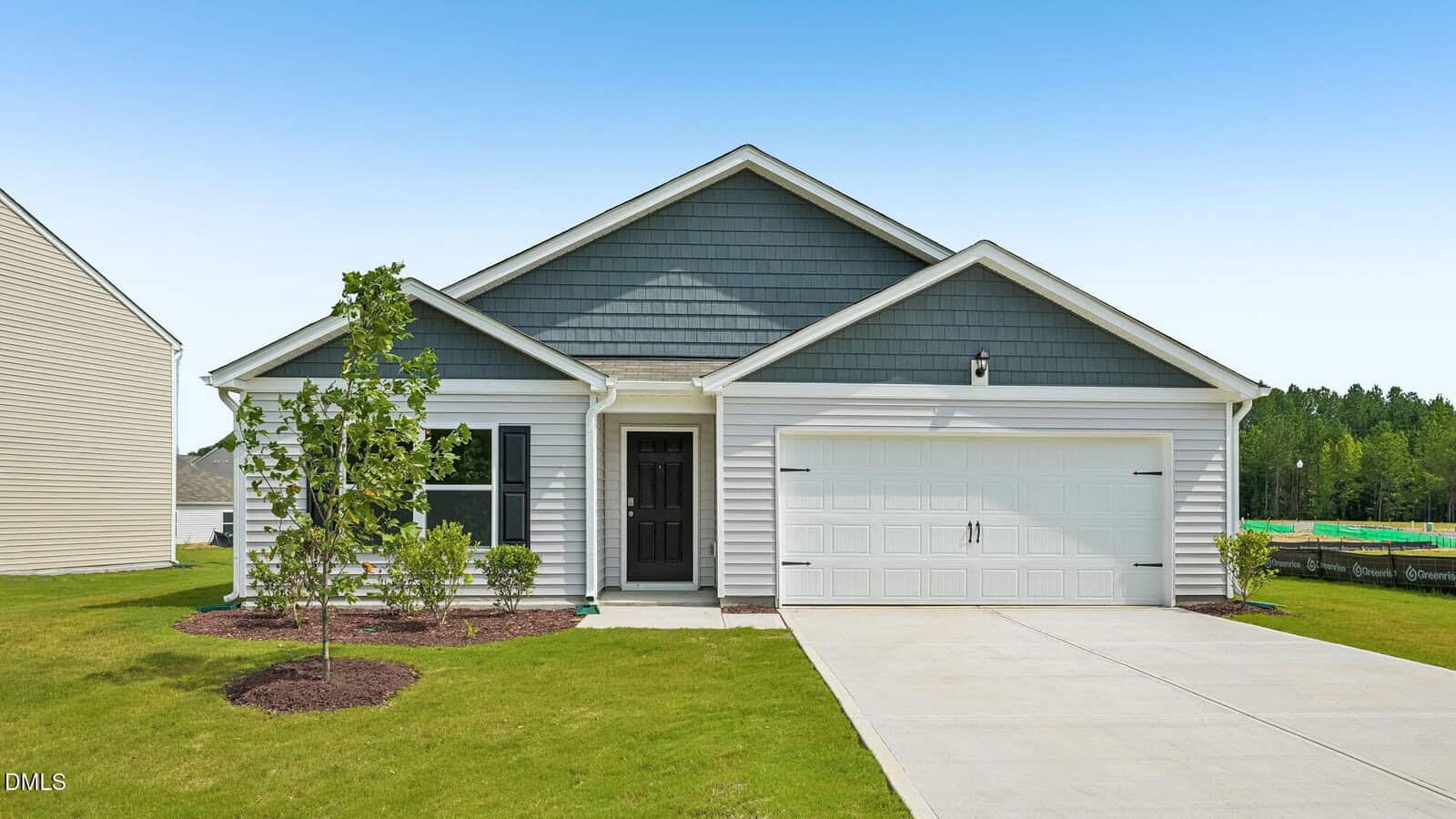 Charming single-story gray house at 86 Richmond Run in Stem, featuring a sleek black front door, attached two-car garage, lush green lawn, young trees, and a clear blue sky in the background.