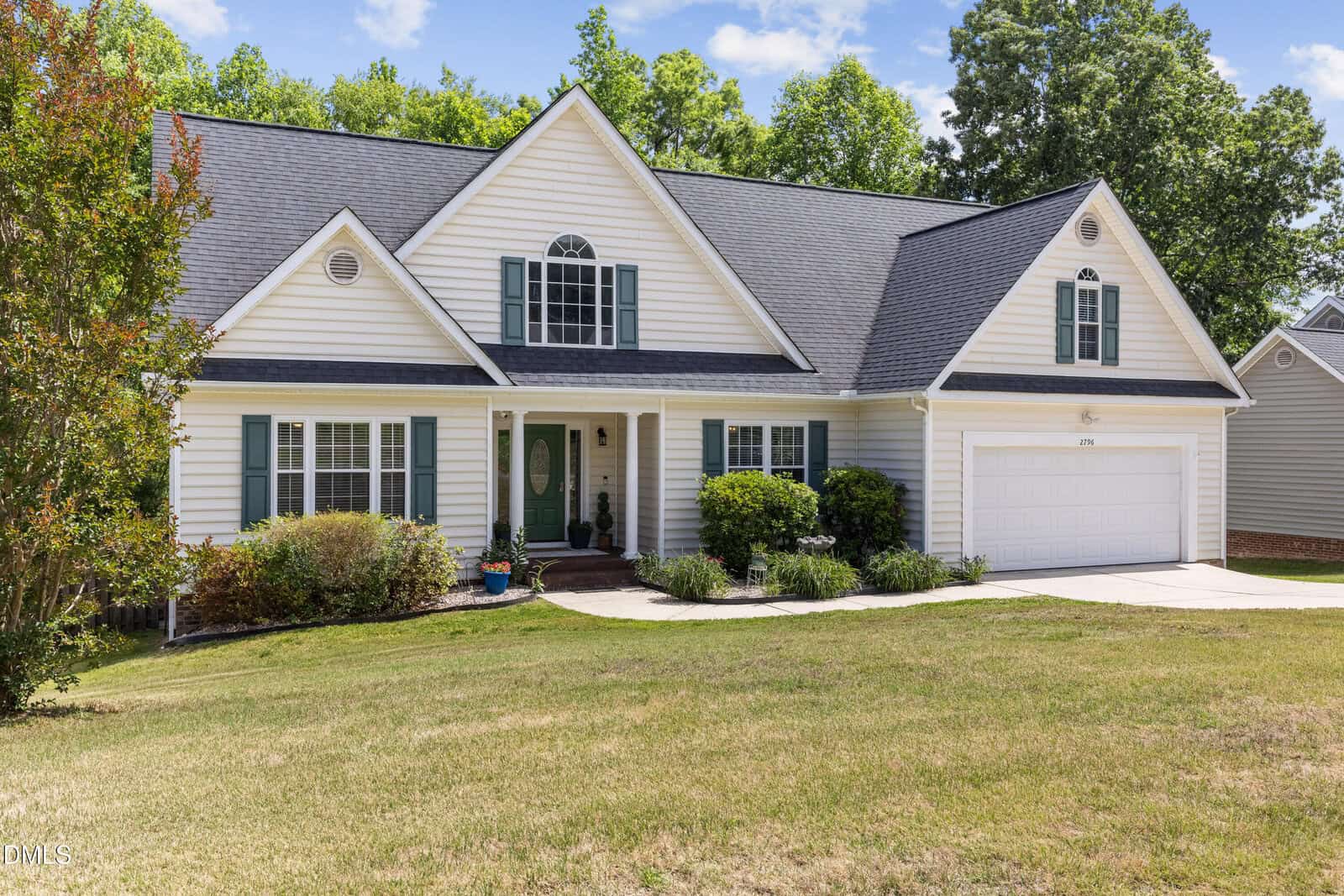 A two-story suburban house at 2796 Clifton Avenue, Creedmoor, with white siding, green shutters, a dark gray roof, double garage, and well-maintained lawn, surrounded by bushes and trees on a sunny day.