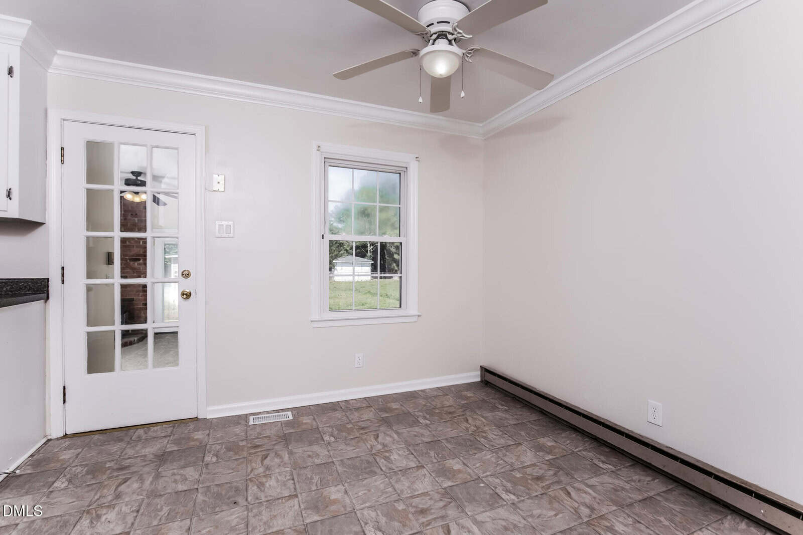 A small, empty room with beige walls, a ceiling fan, tiled floor, a window, and a door with glass panes leading outside.