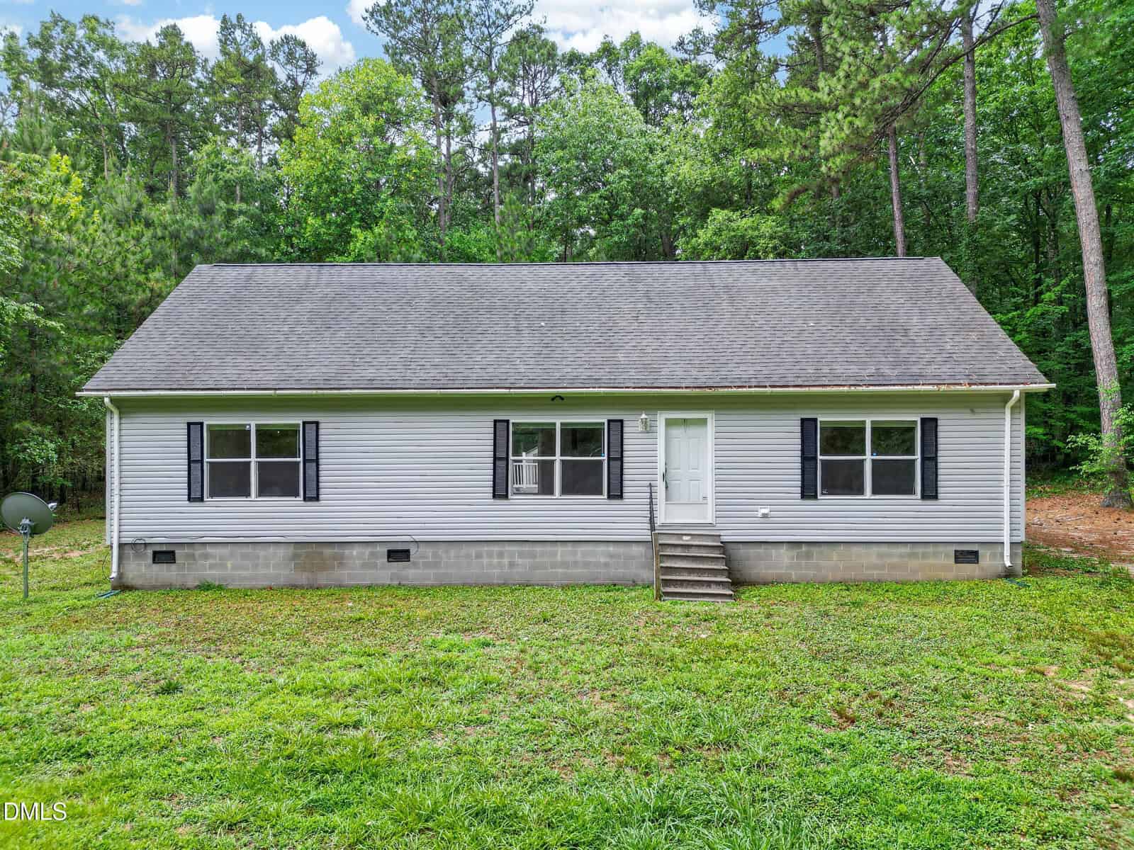 Charming single-story gray house at 126 Hunter Road, Henderson, with black shutters, a white front door, small front steps, and a grassy yard, surrounded by tall trees and dense greenery in the background.