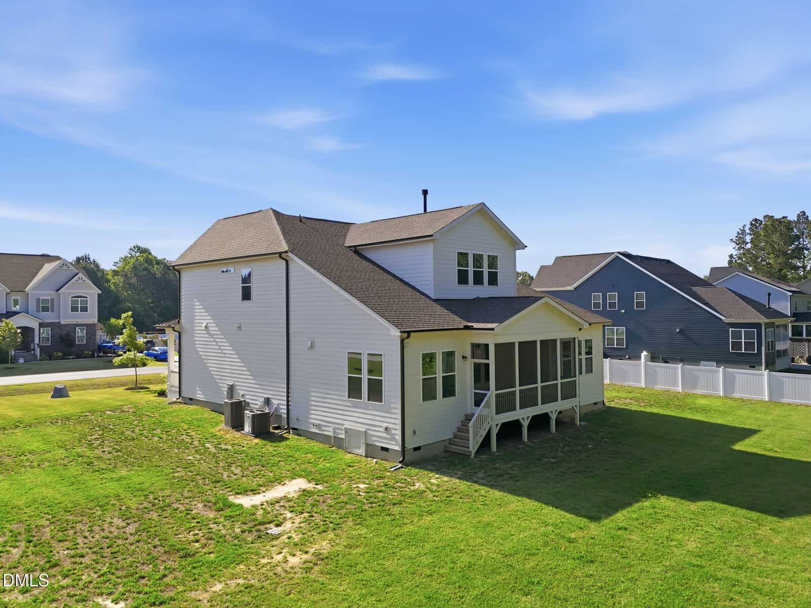 Two-story white house with screened porch, steps leading to a grassy backyard, and neighboring homes nearby. The sky is clear and blue, suggesting a sunny day.