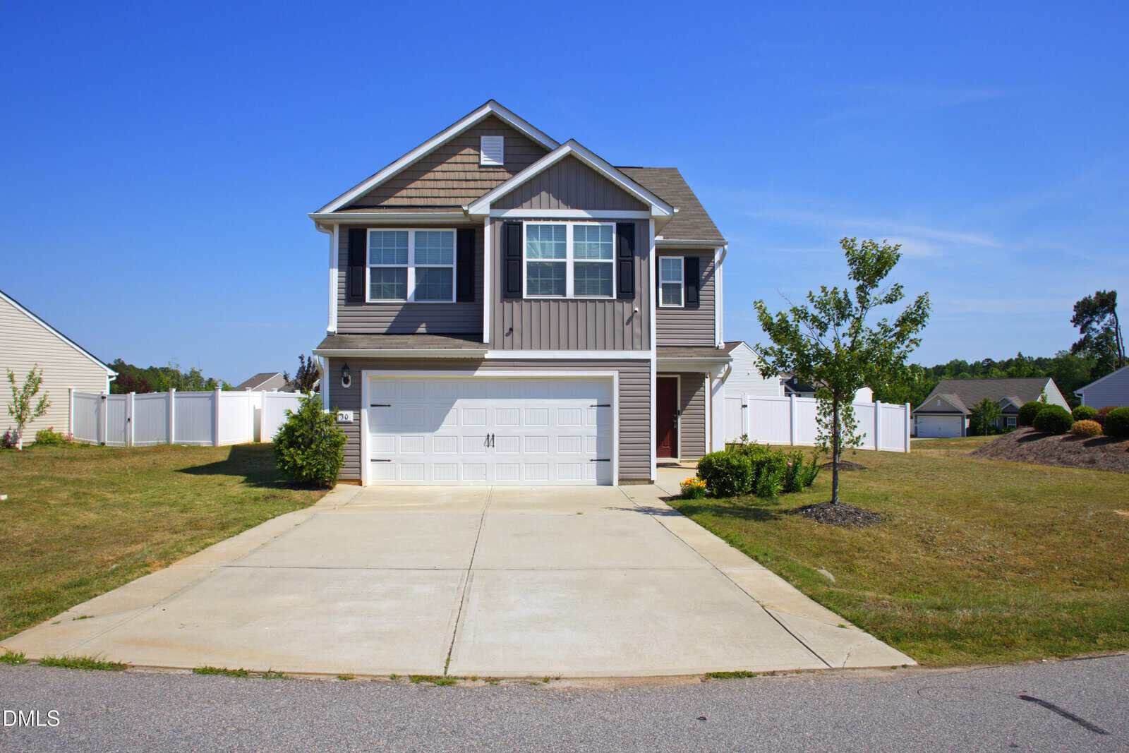 Two-story suburban house at 30 Bounding Lane, Youngsville, with gray siding, white trim, and a double garage. Features a large driveway, small front lawn, young trees, and a white fence under a clear blue sky.
